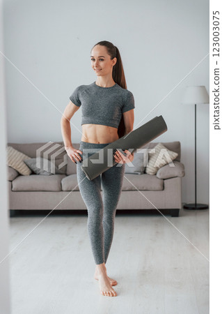Positive yoga instructor. Young woman with slim body type is at home 123003075