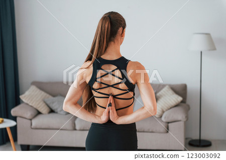 Rear view. Young woman with slim body type and in yoga clothes is at home Rear view. Young woman with slim body type and in yoga clothes is at home 123003092