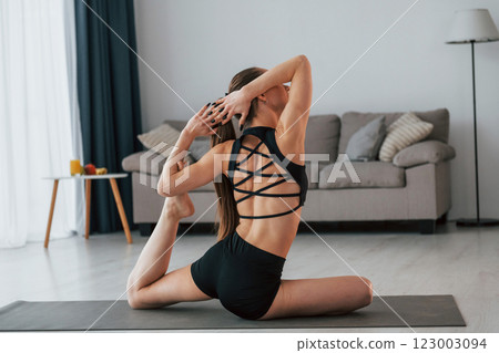 Rear view. Young woman with slim body type and in yoga clothes is at home Rear view. Young woman with slim body type and in yoga clothes is at home 123003094