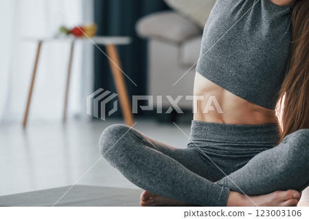 Strong abs. Young woman with slim body type and in yoga clothes is at home Strong abs. Young woman with slim body type and in yoga clothes is at home 123003106