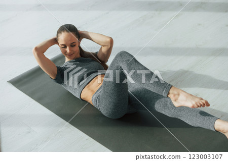 Strong abs. Young woman with slim body type and in yoga clothes is at home Strong abs. Young woman with slim body type and in yoga clothes is at home 123003107