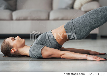 Exercises for spine. Young woman with slim body type and in yoga clothes is at home Exercises for spine. Young woman with slim body type and in yoga clothes is at home 123003110