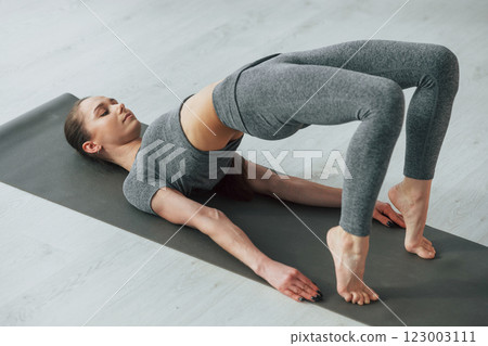 Exercises for spine. Young woman with slim body type and in yoga clothes is at home 123003111