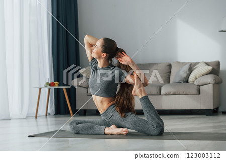Hands stretching. Young woman with slim body type and in yoga clothes is at home 123003112