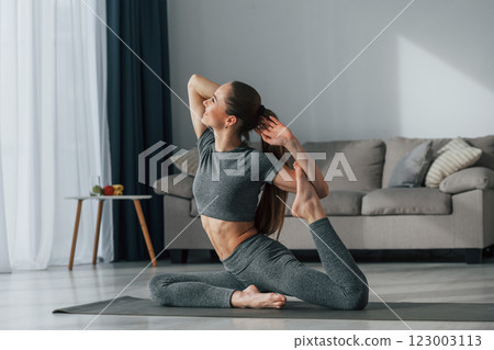 Hands stretching. Young woman with slim body type and in yoga clothes is at home Hands stretching. Young woman with slim body type and in yoga clothes is at home 123003113