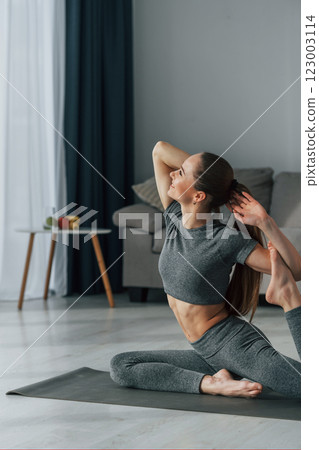 Hands stretching. Young woman with slim body type and in yoga clothes is at home Hands stretching. Young woman with slim body type and in yoga clothes is at home 123003114