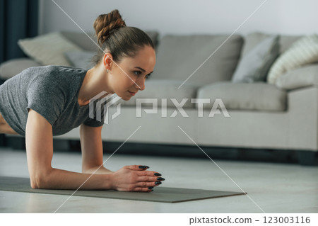 Exercises for spine. Young woman with slim body type and in yoga clothes is at home Exercises for spine. Young woman with slim body type and in yoga clothes is at home 123003116