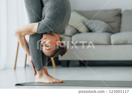 Close up view. Young woman with slim body type and in yoga clothes is at home Close up view. Young woman with slim body type and in yoga clothes is at home 123003117