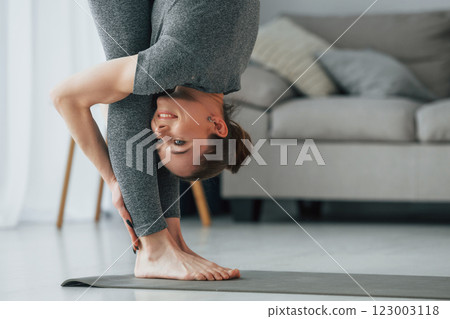 Big stretches. Young woman with slim body type and in yoga clothes is at home 123003118