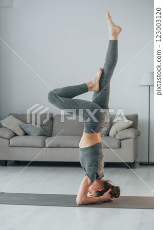 Big stretches. Young woman with slim body type and in yoga clothes is at home 123003120