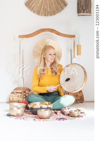 Young cheerful woman performing music therapy session with traditional instruments. Sound meditation, body healing. Seven chakras. Healthcare recreation process 123003194