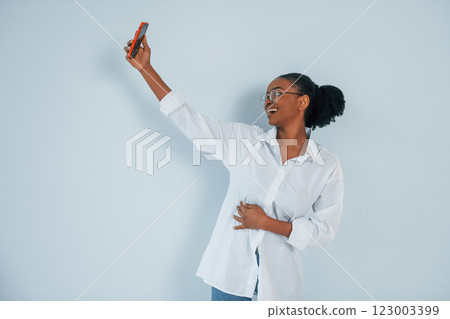 Taking selfie. Young african american woman is against white background Taking selfie. Young african american woman is against white background 123003399