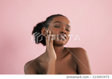 Conception of make up and beauty. Portrait of young african american woman that is against pink background Conception of make up and beauty. Portrait of young african american woman that is against pink background 123003473