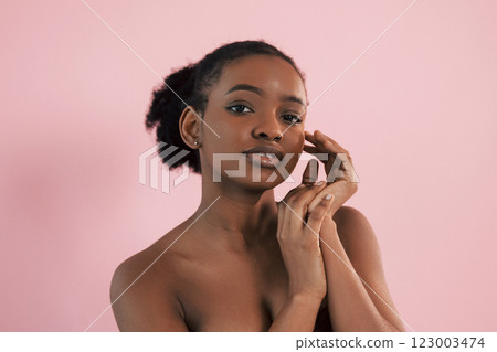 Conception of make up and beauty. Portrait of young african american woman that is against pink background Conception of make up and beauty. Portrait of young african american woman that is against pink background 123003474