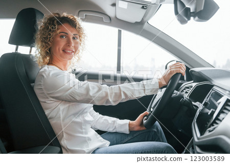 Side view. Woman with curly blonde hair is in autosalon 123003589