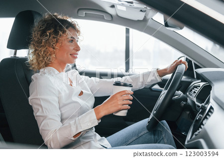 Side view. Woman with curly blonde hair is in autosalon Side view. Woman with curly blonde hair is in autosalon 123003594