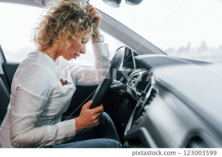 Vehicle interior. Woman with curly blonde hair is in autosalon Vehicle interior. Woman with curly blonde hair is in autosalon 123003599