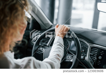 Rear view. Woman with curly blonde hair is in autosalon 123003606