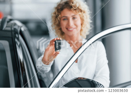 Opening the door. Woman with curly blonde hair is in autosalon 123003630