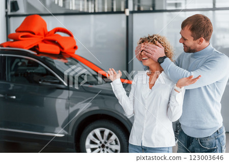 Closing her eyes by hands. Husband makes gift for his wife. Modern new car 123003646
