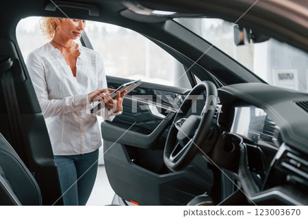 View of vehicle interior. Woman with curly blonde hair is in autosalon 123003670