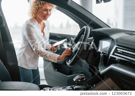 View of vehicle interior. Woman with curly blonde hair is in autosalon View of vehicle interior. Woman with curly blonde hair is in autosalon 123003672
