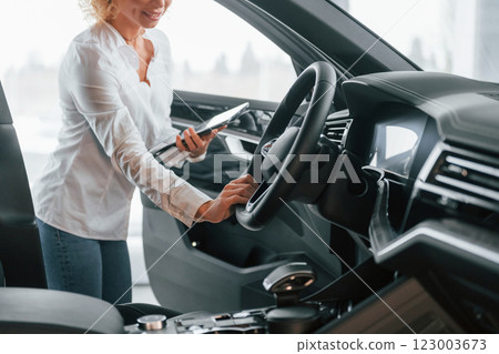 View of vehicle interior. Woman with curly blonde hair is in autosalon 123003673