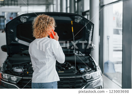 Modern technologies. Woman with curly blonde hair is in autosalon Modern technologies. Woman with curly blonde hair is in autosalon 123003698