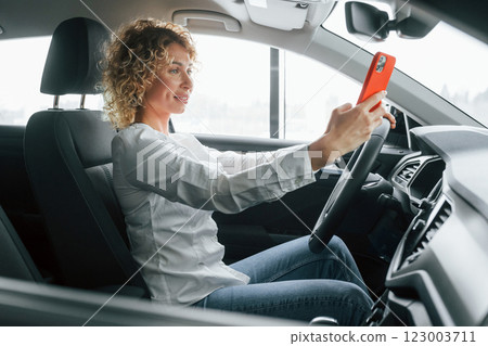 Woman with curly blonde hair is in autosalon 123003711