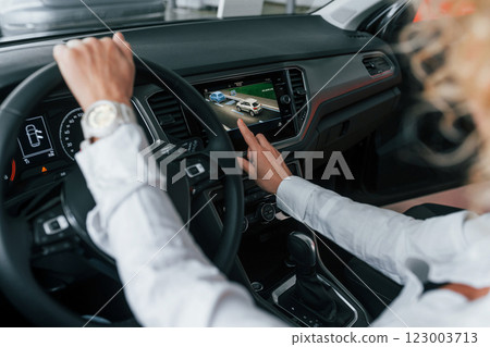 Doing test drive. Woman with curly blonde hair is in autosalon Doing test drive. Woman with curly blonde hair is in autosalon 123003713