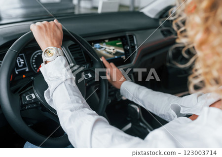 Doing test drive. Woman with curly blonde hair is in autosalon Doing test drive. Woman with curly blonde hair is in autosalon 123003714