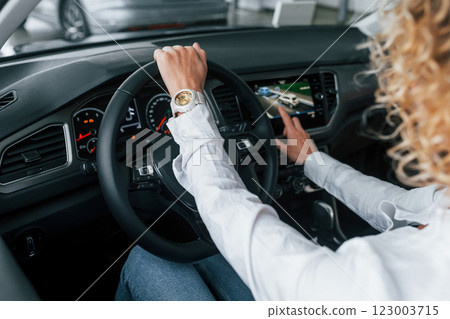 Doing test drive. Woman with curly blonde hair is in autosalon Doing test drive. Woman with curly blonde hair is in autosalon 123003715