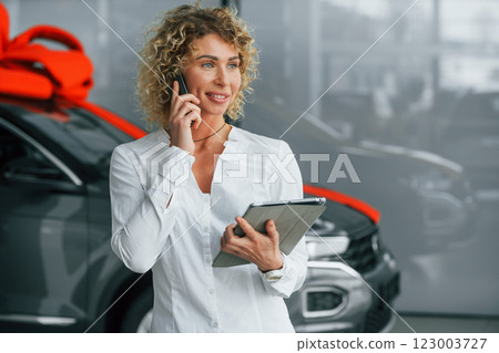 Expensive gift. Woman with curly blonde hair is in autosalon 123003727