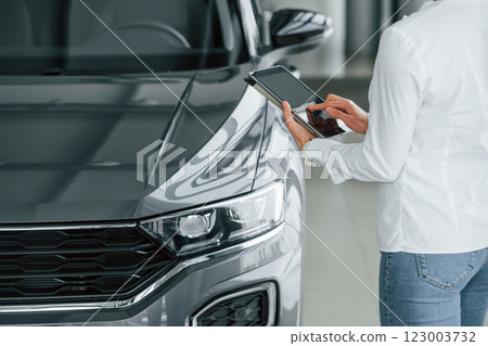 Standing near car. Woman is in autosalon at daytime 123003732