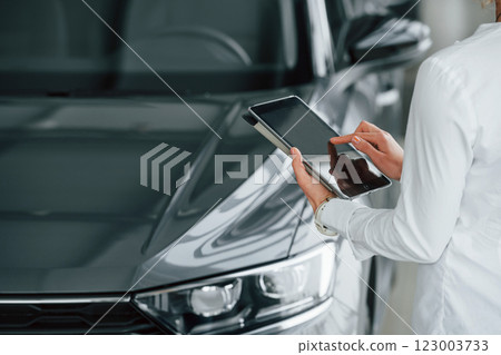 Standing near car. Woman is in autosalon at daytime 123003733