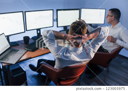 Analizing graphs together. Two stock traders working in the office with exchange technology Analizing graphs together. Two stock traders working in the office with exchange technology 123003975