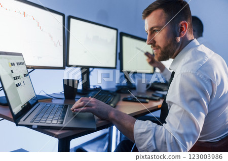 With laptop on the table. Two stock traders working in the office with exchange technology 123003986