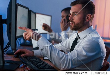 Side view. Two stock traders working in the office with exchange technology 123004011