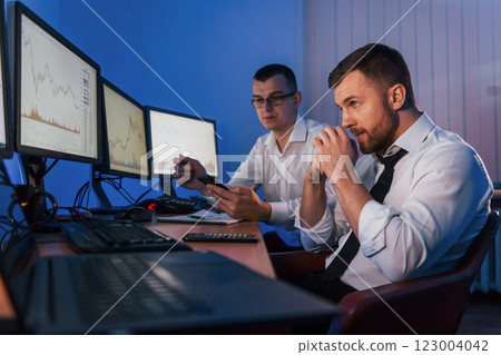 Different information on screens. Two stock traders working in the office with exchange technology 123004042