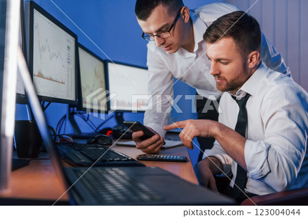 Different information on screens. Two stock traders working in the office with exchange technology Different information on screens. Two stock traders working in the office with exchange technology 123004044