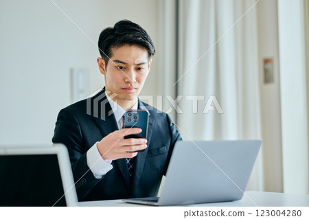 A young man in his twenties operating a smartphone 123004280