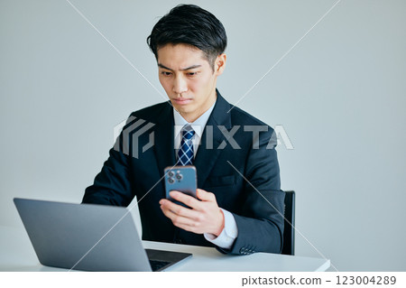 一名20多歲的年輕人正在操作智慧型手機 一名20多歲的年輕人正在操作智慧型手機 123004289