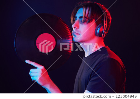 With vinyl record in hands. Man standing in the studio with neon light 123004949