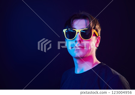 In yellow sunglasses. Man standing in the studio with neon light 123004956