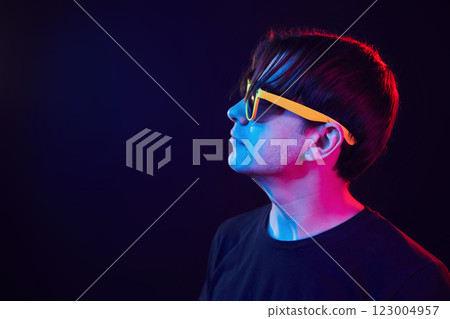 In yellow sunglasses. Man standing in the studio with neon light 123004957