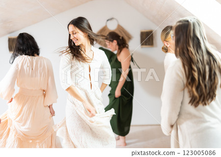 Group of cheerful women all ages, happy people dancing together wearing traditional colorful dresses and hippy clothes. Free people enjoying leisure activity, emphasizing friendship, fun, movement. 123005086