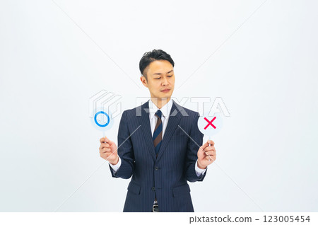 一位中年男性商人感到困惑,舉著一塊寫著「是」的牌子 一位中年男性商人感到困惑,舉著一塊寫著「是」的牌子 123005454
