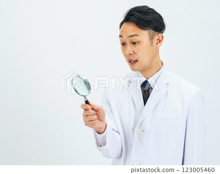 一位身穿白大褂的中年男性醫生/研究員用放大鏡發現了一些東西 123005460