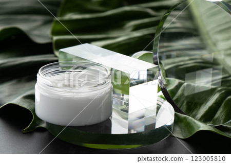 Cream container elegantly positioned on glass against a lush tropical background. Cream container elegantly positioned on glass against a lush tropical background. 123005810