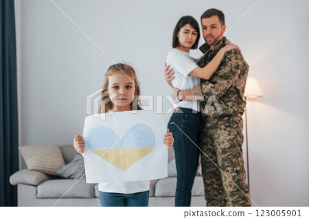 Stop war in Ukraine conception. Soldier in uniform is at home with his wife and daughter 123005901